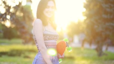 Spor, yaşam tarzı, Extreme and people konsepti, güneşli havada şehirde yollarda güzel bir kız. Günbatımında uzun bir sörf tahtasıyla gülümseyen hippi kız portresi. Yavaş çekim