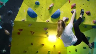 Fitness, ekstrem sporlar, kayalar, insanlar ve sağlıklı yaşam tarzı konsepti. Spor salonunun duvarına tırmanan genç bir kadın.