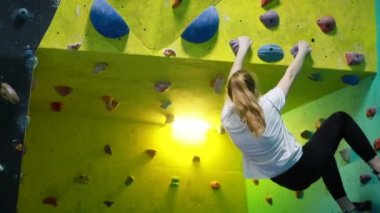 Fitness, ekstrem sporlar, kayalar, insanlar ve sağlıklı yaşam tarzı konsepti. Spor salonunun duvarına tırmanan genç bir kadın.