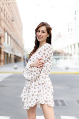 Genç çekici düşünceli kadın güzel elbise düşünceli bir şekilde kameraya bakıyor rahat şehir caddesinde duruyor.