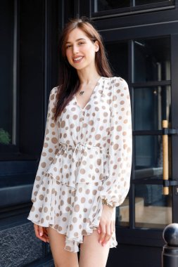 Genç çekici düşünceli kadın güzel elbise düşünceli bir şekilde kameraya bakıyor rahat şehir caddesinde duruyor.