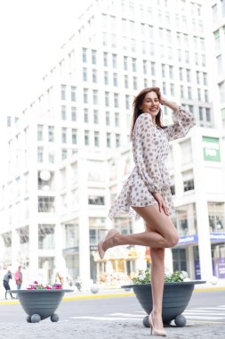 Genç çekici düşünceli kadın güzel elbise düşünceli bir şekilde kameraya bakıyor rahat şehir caddesinde duruyor.