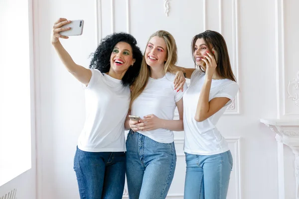 3人の魅惑的な多民族の女性が一緒に立って笑顔の肖像画 携帯電話で自撮りする3人の美しい笑顔のガールフレンド 自画像を撮り — ストック写真