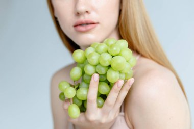 Bej rengi mayo giyen kadın izole edildi. Mayo Modeli. Rio Bottoms, Brabrassiere. Kızlar Özeti. Kadın mayo iç çamaşırı. Kadın göğsünde üzüm tutuyor ve iki eliyle sarılıyor..