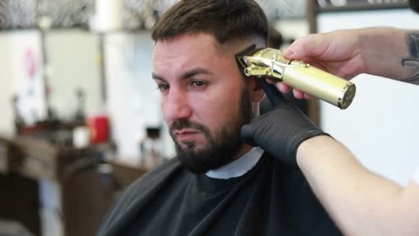 Jovem Barbearia Senta Numa Poltrona Barbeiro Corta Cabelo Com Trimer — Vídeo de Stock