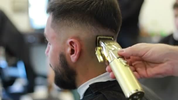 Młody Człowiek Salonie Fryzjerskim Siedzi Fotelu Fryzjer Obcina Włosy Przycinaczem — Wideo stockowe