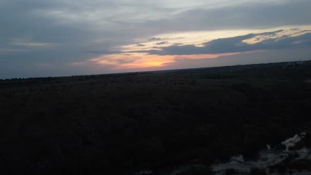 空中摄影无人驾驶飞机拍摄山河 向后飞越一座山 夕阳西下经过绿河岸 小岩石喷出急流 水面阳光普照 — 图库视频影像