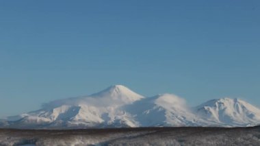 Kamçatka zaman aşımı: Petropavlovsk-Kamçatsky şehrinin arka planda gökyüzünde sürüklenen güzel bulutlar ve Koryak Volkanı (Koryaksky Volkanı) konisi. Kamçatka Yarımadası, Rus Uzak Doğusu