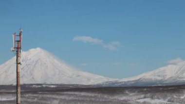 Kamçatka zaman aşımı: Petropavlovsk-Kamçatsky şehrinin arka planda gökyüzünde sürüklenen güzel bulutlar ve Koryak Volkanı (Koryaksky Volkanı) konisi. Kamçatka Yarımadası, Rus Uzak Doğusu