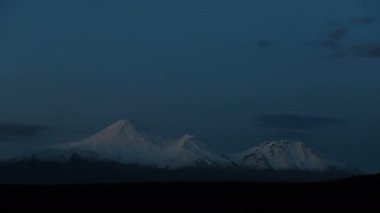 Kamçatka zaman aşımı: Petropavlovsk-Kamçatsky şehrinin arka planda gökyüzünde sürüklenen güzel bulutlar ve Koryak Volkanı (Koryaksky Volkanı) konisi. Kamçatka Yarımadası, Rus Uzak Doğusu
