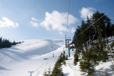 Güneşli bir günde kar kaplı ağaçlarla kayak pisti ve sandalye kaldırma. Combloux kayak alanı, Fransız Alpleri