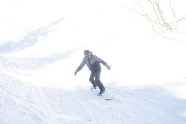 Kış, eğlence, spor ve insan konsepti - güneşli bir günde dağlarda atlayan aktif snowboardcu. Snowboard yakın plan. Sheregesh Kayak Merkezi