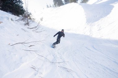 Kış, eğlence, spor ve insan konsepti - güneşli bir günde dağlarda atlayan aktif snowboardcu. Snowboard yakın plan. Sheregesh Kayak Merkezi