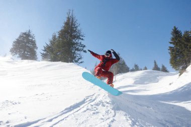Kış, eğlence, spor ve insan konsepti - güneşli bir günde dağlarda atlayan aktif snowboardcu. Snowboard yakın plan. Sheregesh Kayak Merkezi