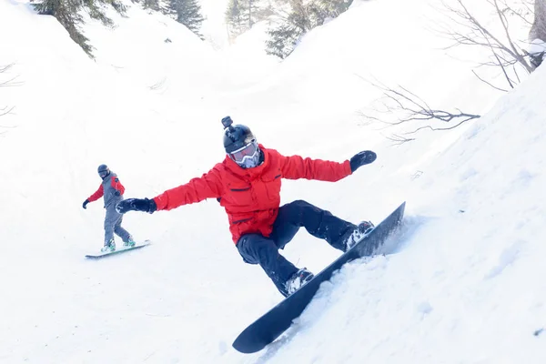 winter, leisure, sport and people concept - Active snowboarder jumping in mountains on a sunny day. Snowboarding closeup. Sheregesh ski resort