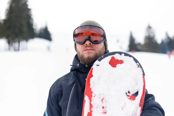 winter, leisure, sport and people concept - Man snowboarding in the mountains. Snowboarder resting on mountain top on a background of blue sky. Ski resort.