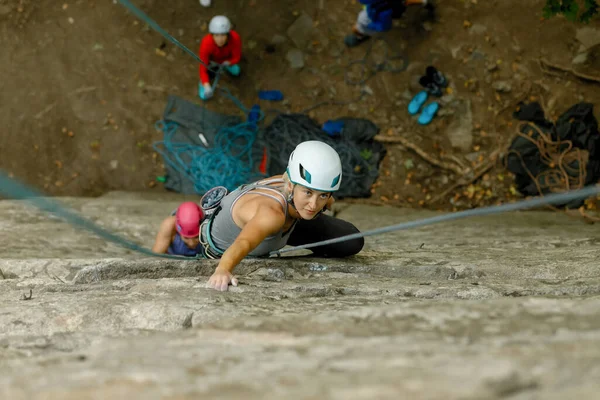 fitness, extreme sport and healthy lifestyle concept - Climber overcomes challenging climbing route. A girl climbs a rock. Woman engaged in extreme sport. Extreme hobby.