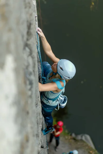 fitness, extreme sport and healthy lifestyle concept - Climber overcomes challenging climbing route. A girl climbs a rock. Woman engaged in extreme sport. Extreme hobby.