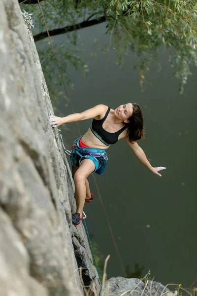 fitness, extreme sport and healthy lifestyle concept - Climber overcomes challenging climbing route. A girl climbs a rock. Woman engaged in extreme sport. Extreme hobby.