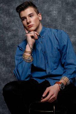 Kot gömlekli adam, kolları kalçasında, gri arka planı var. İnsanların yaşam tarzı konsepti. Kopyalama alanı oluşturun. Kolları düzeltiyorum. Eldeki zincir