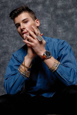 Kot gömlekli adam, kolları kalçasında, gri arka planı var. İnsanların yaşam tarzı konsepti. Kopyalama alanı oluşturun. Kolları düzeltiyorum. Eldeki zincir