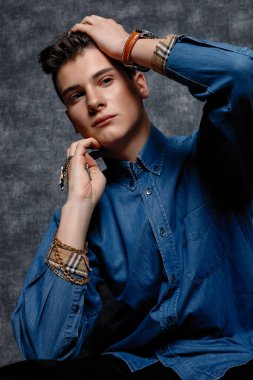 Kot gömlekli adam, kolları kalçasında, gri arka planı var. İnsanların yaşam tarzı konsepti. Kopyalama alanı oluşturun. Kolları düzeltiyorum yana bakıyorum.