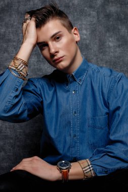 Kot gömlekli adam, kolları kalçasında, gri arka planı var. İnsanların yaşam tarzı konsepti. Kopyalama alanı oluşturun. Kolları düzeltiyorum yana bakıyorum.