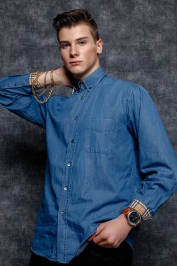 Kot gömlekli adam, kolları kalçasında, gri arka planı var. İnsanların yaşam tarzı konsepti. Kopyalama alanı oluşturun. Kolları düzeltiyorum yana bakıyorum.