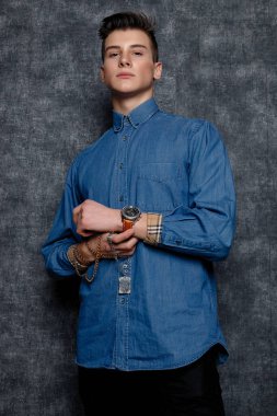 Kot gömlekli adam, kolları kalçasında, gri arka planı var. İnsanların yaşam tarzı konsepti. Kopyalama alanı oluşturun. Kolları düzeltiyorum yana bakıyorum.