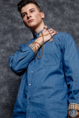 Kot gömlekli adam, kolları kalçasında, gri arka planı var. İnsanların yaşam tarzı konsepti. Kopyalama alanı oluşturun. Kolları düzeltiyorum yana bakıyorum.