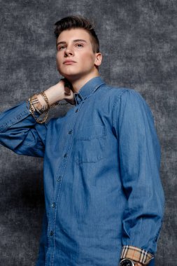 Kot gömlekli adam, kolları kalçasında, gri arka planı var. İnsanların yaşam tarzı konsepti. Kopyalama alanı oluşturun. Kolları düzeltiyorum yana bakıyorum.