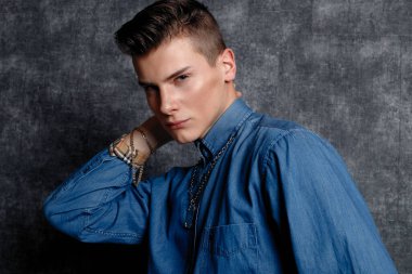 Kot gömlekli adam, kolları kalçasında, gri arka planı var. İnsanların yaşam tarzı konsepti. Kopyalama alanı oluşturun. Kolları düzeltiyorum yana bakıyorum.