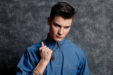 Kot gömlekli adam, kolları kalçasında, gri arka planı var. İnsanların yaşam tarzı konsepti. Kopyalama alanı oluşturun. Kolları düzeltiyorum. ciddi