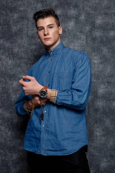 Kot gömlekli adam, kolları kalçasında, gri arka planı var. İnsanların yaşam tarzı konsepti. Kopyalama alanı oluşturun. Kolları düzeltiyorum yana bakıyorum.