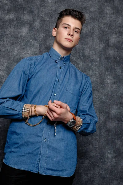 Kot gömlekli adam, kolları kalçasında, gri arka planı var. İnsanların yaşam tarzı konsepti. Kopyalama alanı oluşturun. Kolları düzeltiyorum yana bakıyorum.