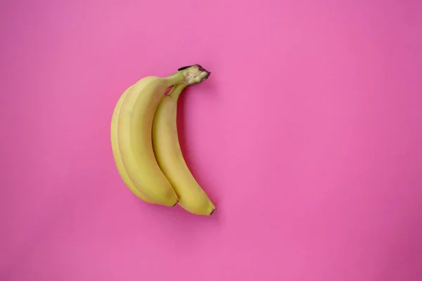 Single banana on a pink background with strong shadow. three bananas