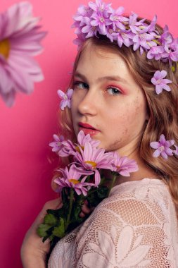 Young model with floral accessories in hair, promoting spring fashion and natural beauty concept.