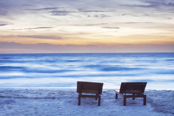 Lynnig sunset beach med två solstolar och suddig havet — Stockfoto