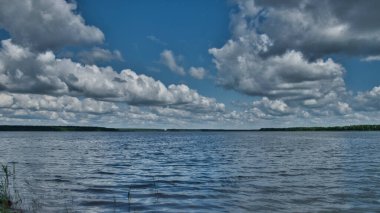 Geniş bir nehir ya da gölün kıyısında çan kulesi olan küçük beyaz bir kilise.