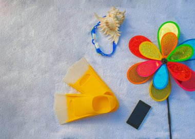 Plaj aksesuarları güneşte beyaz bir havluda yatıyor, arka plan, düz döşeme, mayo, parmak arası terlik, kabuk, çocuk pikabı.