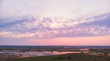Bulutlu, yumuşak bir şafak veya gün batımının arka planında nehir taşar. Yatay fotoğraf 16: 9, havadan çekilmiş fotoğraflar.