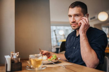 Adam kafede oturan ve akşam yemeği. Ayrıca o telefonda konuşurken ve kamera için düz arıyorsunuz. O iyi ve kendinden emin görünüyor.