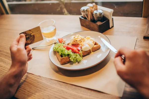 Фотография парней, держащих золотую карту в левой руке. Он держит нож правой рукой. На столе есть тарелка с вкусной едой. Закрыть . — стоковое фото
