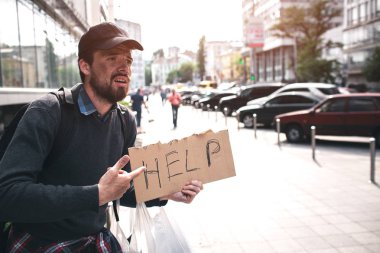 Zavallı adam stnading ve yardım diyor cardbpard işaret var. Umutsuzluk olduğunu. Adam ona yardım etmek için hiç kimsesi yok. Biri ona yardım etmek arıyor.