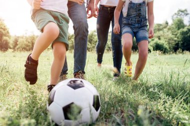 Çayır çim üzerinde uyanma aileler bacaklar bir resim. Futbol oynuyorlar. Bir balo halklar bacaklar önünde oyun için.