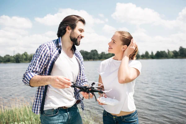 Piękny obraz młody mężczyzna i kobieta razem stojąc i patrząc na siebie nawzajem. Są one w miłości ze sobą. Facet trzyma w rękach drone. Kobieta trzyma ręce na włosy. — Zdjęcie stockowe