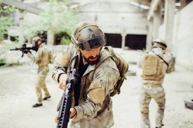 Üç asker büyük ve parlak bir binada duruyor. Sessizlik tutuyorlar. Erkekler çok dikkat ediyorlar. Mücadele etmek ve kendilerini savunmak hazırlar. Adam bir ön aşağı bakıyor.