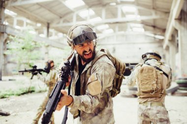 Ciddi adam giyim mühimmat ve çığlık. O bakıyor. Ayrıca adam tüfekle tutar. Suç ortakları onun arkasında duran ve onu korumak. Onlar bir takım çalışması.