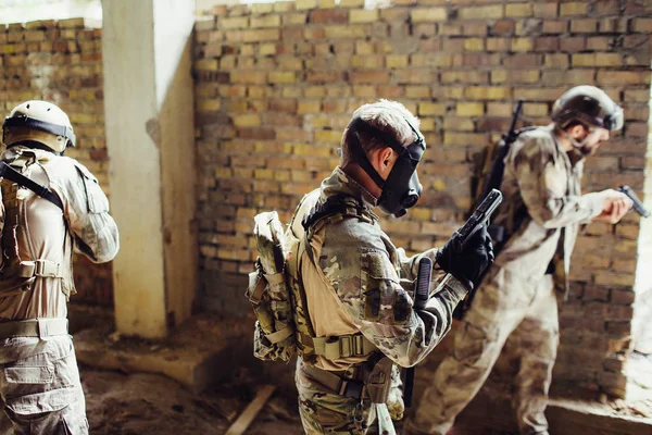 Tre soldati sono nella stanza. Si stanno preparando per una battaglia. I ragazzi hanno le munizioni. Uno di loro ha una maschera nera su Faace. Sono pronti a combattere. . — Foto Stock