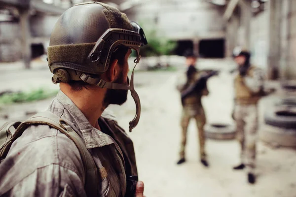 Солдат, який носить уніформу, дивиться на своїх друзів. Вони стоять далеко від нього. Хлопці відпочивають . — стокове фото